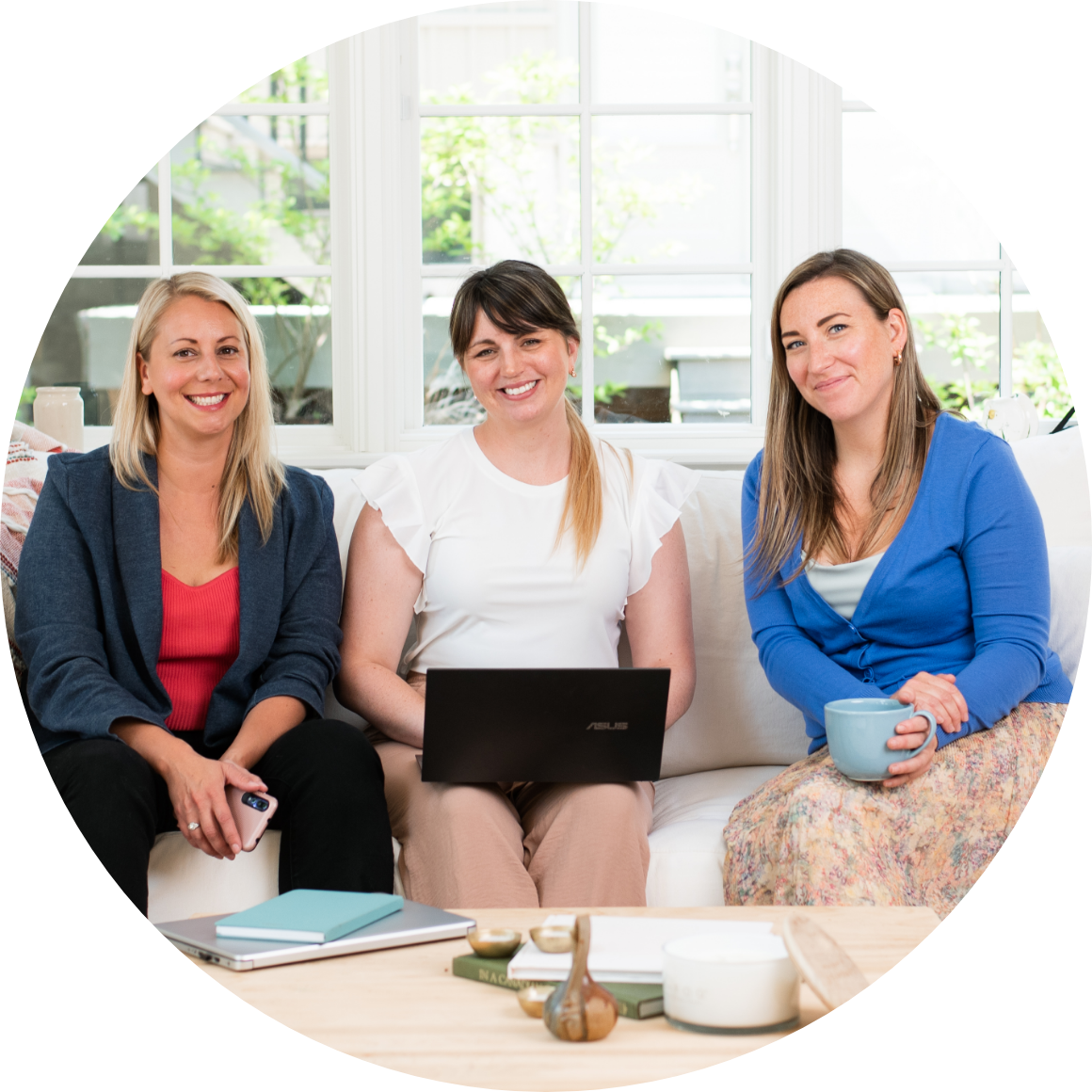 Three women sitting in a row, middle woman has laptop out