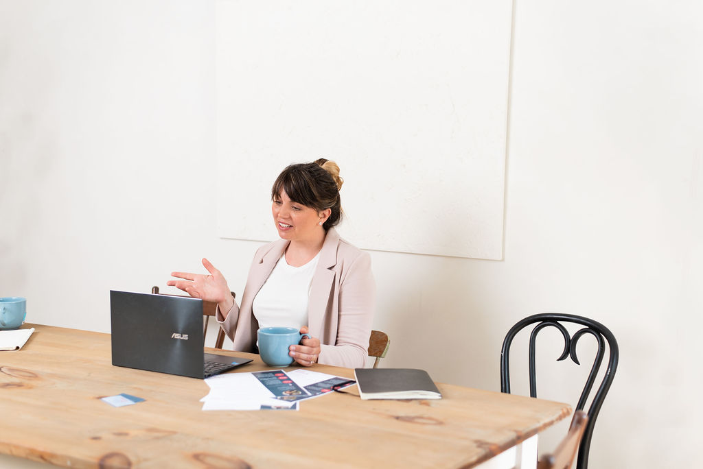 Woman's hands on table with notebook and blue coffee cup