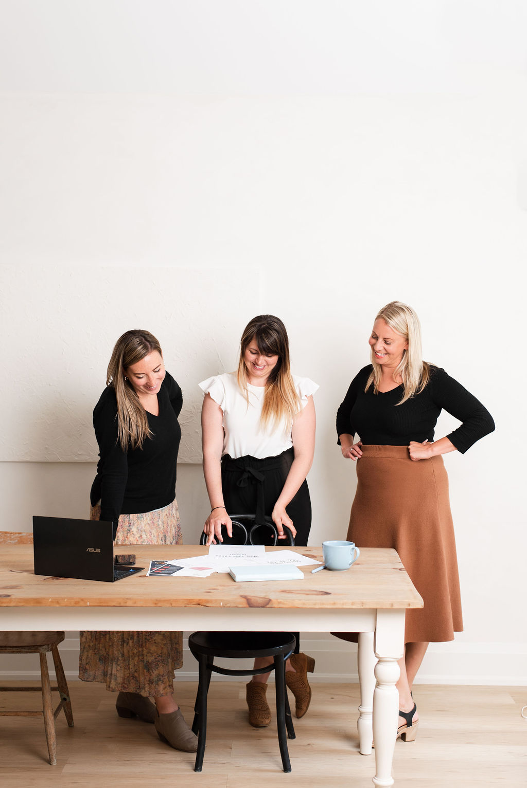 Three women sitting on couch looking at laptop